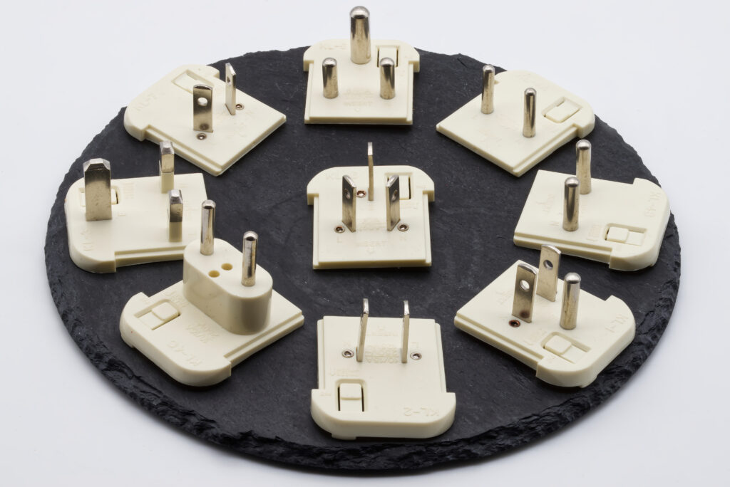 diversos adaptadores de tomada internacional para viagem sobre um mapa mundi